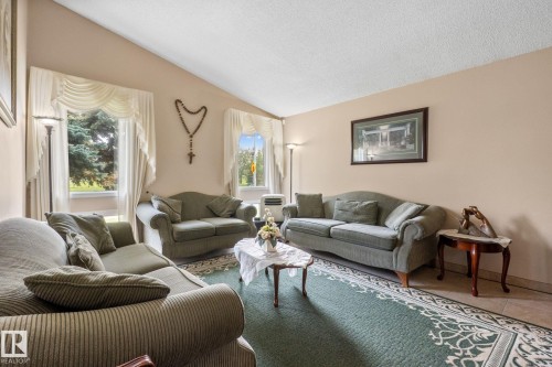 Vaulted ceilings enhance this living area featuring multiple windows, neutral wall tones, and floor tile - 18126 98 Avenue, Edmonton, AB 