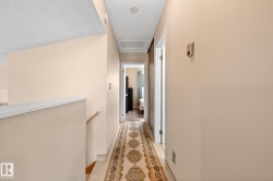 Upper-level hallway featuring a patterned runner over tile flooring and neutral-toned walls - 