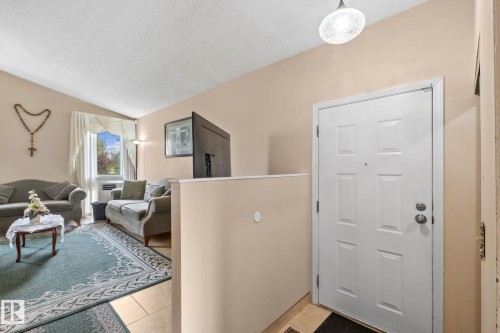 Entry area featuring a paneled door with polished hardware, a decorative ceiling light fixture, and tile flooring - 18126 98 Avenue, Edmonton, AB 