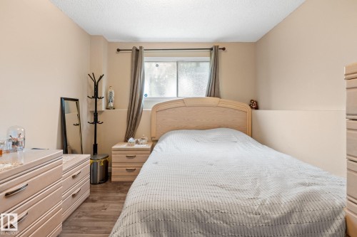 Bedroom space featuring wood-finish flooring, a window with drapery, and neutral-toned walls - 18126 98 Avenue, Edmonton, AB 