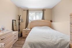 Bedroom space featuring wood-finish flooring, a window with drapery, and neutral-toned walls - 