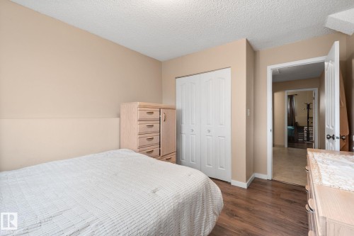 Bedroom featuring wood-finish flooring, neutral wall paint, and a built-in closet with white bifold doors - 18126 98 Avenue, Edmonton, AB 