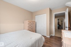 Bedroom featuring wood-finish flooring, neutral wall paint, and a built-in closet with white bifold doors - 