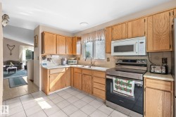 Kitchen featuring wood cabinetry, white tile flooring, a stainless steel range, and a built-in microwave - 