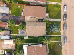 Aerial view highlighting a residential property with a shingle roof and a paved driveway - 