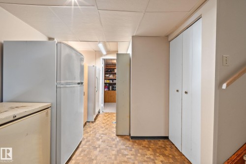Utility space featuring wood-finish flooring, drop ceiling, white walls, and built-in storage closets - 18126 98 Avenue, Edmonton, AB 
