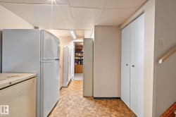 Utility space featuring wood-finish flooring, drop ceiling, white walls, and built-in storage closets - 