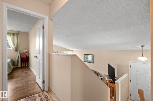 Interior hallway featuring wood-finish flooring, a white paneled door, and neutral wall paint - 18126 98 Avenue, Edmonton, AB 
