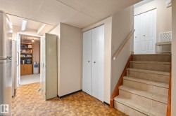 Tiled staircase with wood handrail, presenting access to an upper level - 
