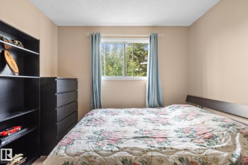 Bright room featuring a window with green tree scenery, light-toned walls, and a textured ceiling - 18126 98 Avenue, Edmonton, AB 
