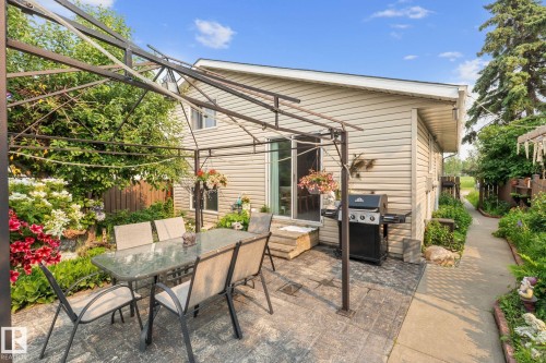 Expansive outdoor patio area featuring a metal gazebo frame, stamped concrete patio, and mature perimeter landscaping - 18126 98 Avenue, Edmonton, AB 