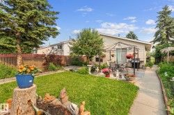 Expansive backyard featuring a lush lawn, mature trees, and a paved patio area - 