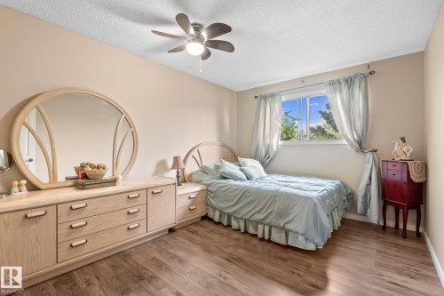 Bedroom featuring wood-finish flooring, a window with natural light, a ceiling fan with integrated lighting, and neutral wall tones - 18126 98 Avenue, Edmonton, AB 