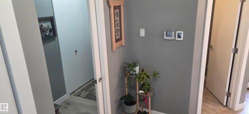 Hallway featuring light gray walls, white trim, and light wood-finish flooring - 16505 133 Street, Edmonton, AB 