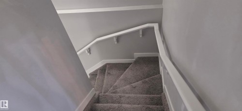 Carpeted staircase with white trim, white handrail, and light gray wall paint - 16505 133 Street, Edmonton, AB 