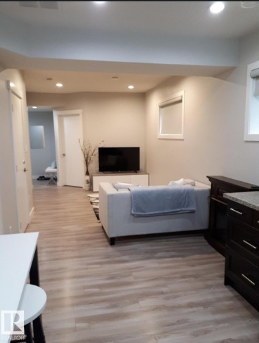 Open-concept living area featuring wood-finish flooring, recessed lighting, and neutral wall tones - 16505 133 Street, Edmonton, AB 