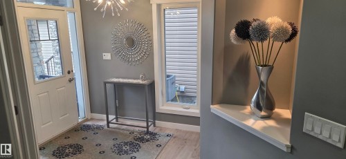 Entryway featuring light wood-finish flooring, a white paneled door with glass inserts, and a built-in display nook with a white shelf - 16505 133 Street, Edmonton, AB 