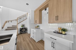 Contemporary kitchen with light wood-finish upper cabinetry, white lower cabinetry, and black hardware - 