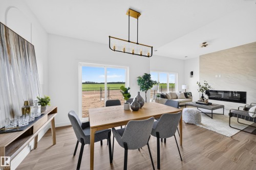 Open-concept living area featuring wood-finish flooring, a linear electric fireplace with a stone surround, and abundant natural light from large windows - 523 Ashgrove Circle, Leduc, AB 