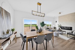 Open-concept living area featuring wood-finish flooring, a linear electric fireplace with a stone surround, and abundant natural light from large windows - 
