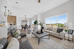 Open-concept living space featuring wood-finish flooring, a contemporary kitchen with a peninsula and pendant lighting, and a dining area - 