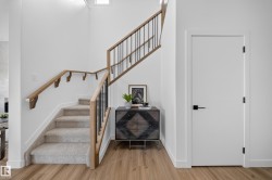 Staircase featuring wood handrails and black metal balusters, carpeted treads, and wood-finish flooring - 