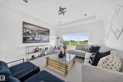 Bright living area featuring a large picture window, recessed lighting, and a tray ceiling - 