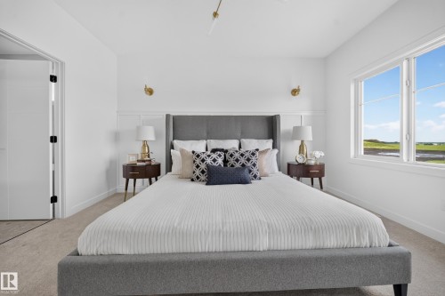 Carpeted bedroom with a large window and white trim - 523 Ashgrove Circle, Leduc, AB 