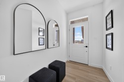 Entryway featuring wood-finish flooring, white walls, and a door with a clear glass insert and transom window - 