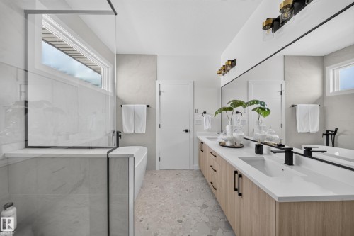 Modern bathroom featuring a dual vanity with light wood-finish cabinetry, white countertops, and black fixtures - 523 Ashgrove Circle, Leduc, AB 