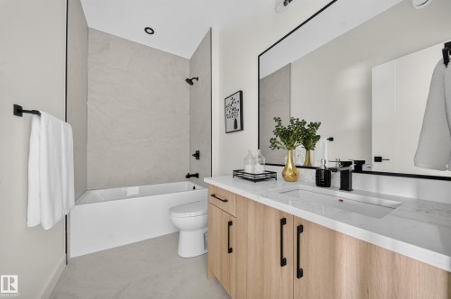 Contemporary bathroom featuring a light wood-finish vanity with black hardware, an integrated sink, and a white countertop - 523 Ashgrove Circle, Leduc, AB 