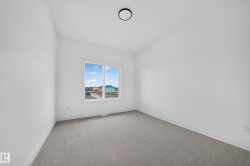 Neutral-toned room featuring a large window, light gray carpeting, and crisp white walls - 