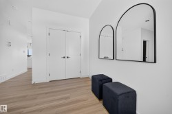 Entryway featuring light wood-finish flooring, white walls, and modern double doors with dark hardware - 