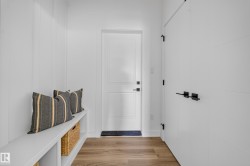 Entryway featuring wood-finish flooring, white paneled walls, and a built-in bench with storage cubbies - 