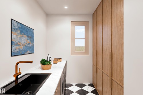 Built-in wood cabinetry with integrated handles, black and white checkered flooring, white countertop, and a single-basin black sink with a bronze faucet - 9138 104 Street, Morinville, AB 