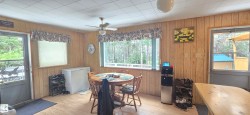 Wood-paneled room featuring wood-finish flooring, a ceiling fan, and two exterior doors - 