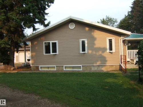 Beige horizontal siding exterior with white trim windows and a white gable vent - 163062 Twp Rd 565, Rural Lamont County, AB 