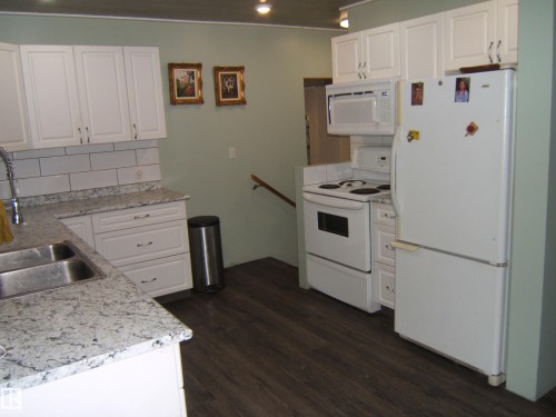 Kitchen featuring white cabinetry, light-colored countertops, subway tile backsplash, and wood-finish flooring - 163062 Twp Rd 565, Rural Lamont County, AB 