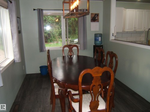 Dining area featuring wood-finish flooring, two windows, and a built-in pass-through opening to the kitchen - 163062 Twp Rd 565, Rural Lamont County, AB 