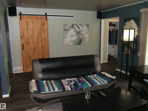 Interior space featuring a natural wood barn door with black hardware, dark wood-finish flooring, and a color palette of light green and deep teal walls - 163062 Twp Rd 565, Rural Lamont County, AB 