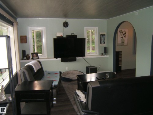 Living area featuring a textured ceiling, arched entryway, two windows, and wood-finish flooring - 163062 Twp Rd 565, Rural Lamont County, AB 