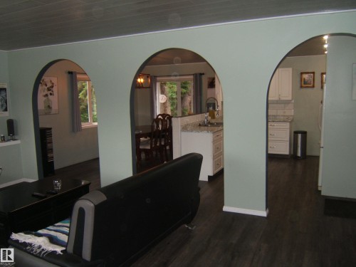 Open concept living spaces featuring multiple arched entryways and dark wood-finish flooring throughout - 163062 Twp Rd 565, Rural Lamont County, AB 