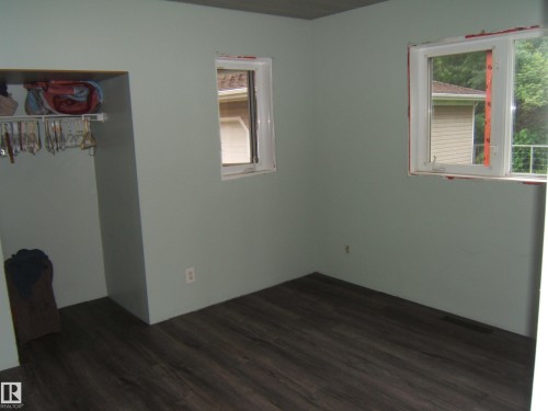 Interior room featuring dark wood-finish flooring, light green walls, and two white-framed windows - 163062 Twp Rd 565, Rural Lamont County, AB 