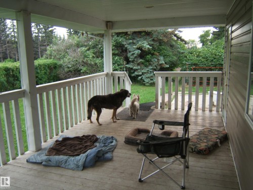 Covered porch featuring white railing, wood-finish flooring, and exterior siding - 163062 Twp Rd 565, Rural Lamont County, AB 