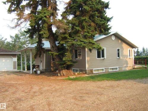 Single-story residence featuring light beige siding, a light blue metal roof, and white-framed windows - 163062 Twp Rd 565, Rural Lamont County, AB 