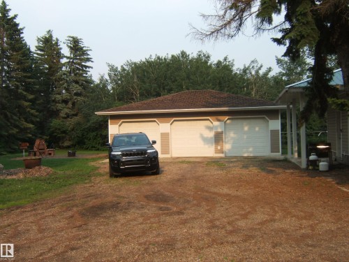 Three-car garage with overhead doors and wood-look siding accents - 163062 Twp Rd 565, Rural Lamont County, AB 