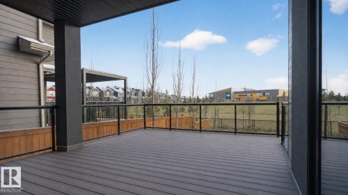 Spacious covered deck featuring composite decking and glass panel railings - 104 Edgewater Circle, Leduc, AB 