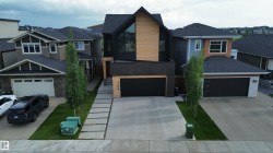 Contemporary architectural design featuring black siding, natural wood-tone accents, and a distinctive peak roofline - 