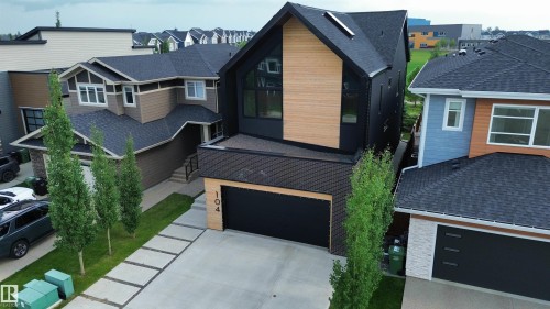 Contemporary black exterior featuring a wood-finish accent facade and large windows - 104 Edgewater Circle, Leduc, AB 