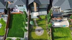 Spacious backyard featuring a manicured lawn, established landscaping, and a fire pit area - 